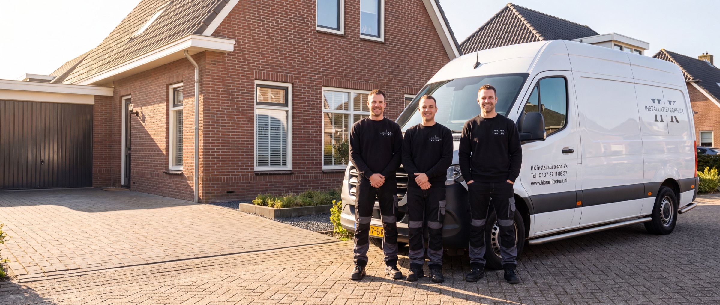 Team van HK Installatietechniek bij de bedrijfsbus voor een woning